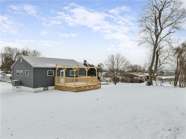 snow covered property featuring metal roof, central AC unit, and a deck