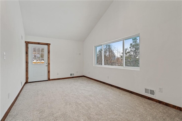 spare room with high vaulted ceiling, light colored carpet, visible vents, and baseboards