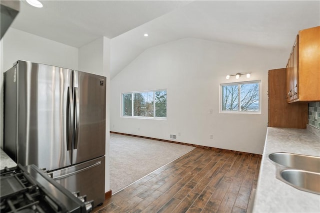 kitchen with a healthy amount of sunlight, brown cabinetry, light countertops, and freestanding refrigerator