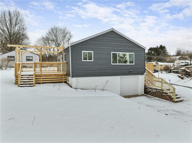 snow covered property with a deck and an attached garage