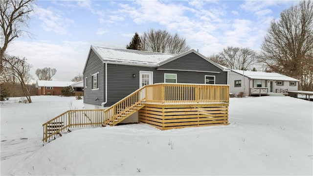 snow covered house with stairs and a wooden deck