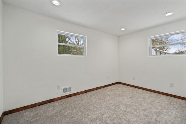 carpeted spare room featuring baseboards, visible vents, and recessed lighting