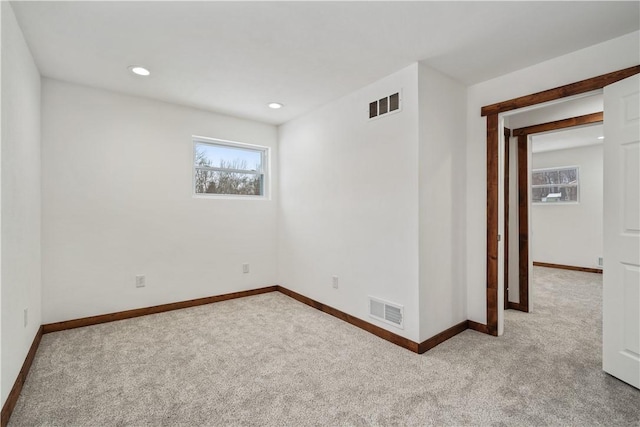 spare room with baseboards, visible vents, and light colored carpet