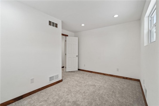 empty room featuring recessed lighting, light colored carpet, visible vents, and baseboards