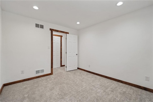 empty room featuring baseboards, visible vents, and light colored carpet