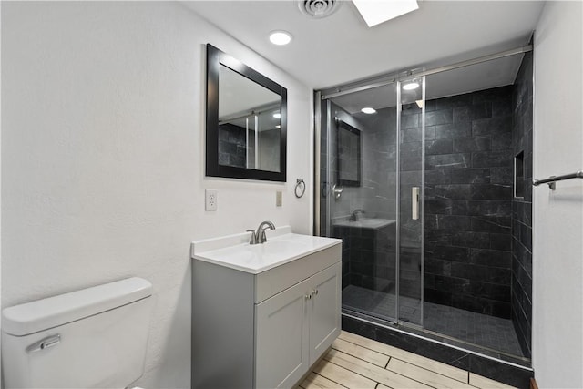 full bath with wood finish floors, visible vents, toilet, a shower stall, and vanity