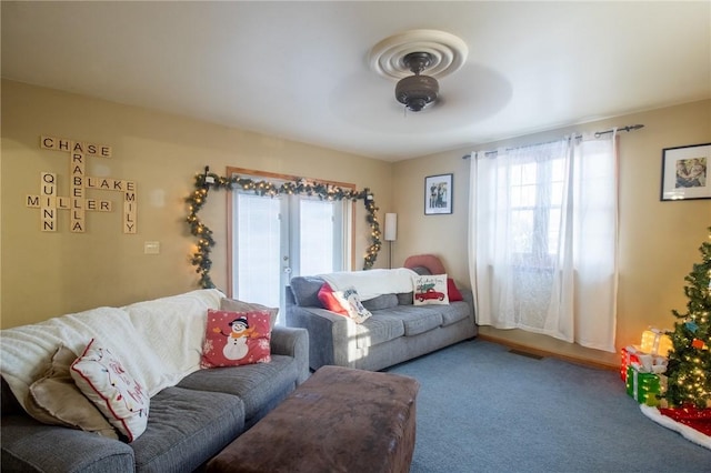 living room featuring ceiling fan, visible vents, carpet, and a wealth of natural light