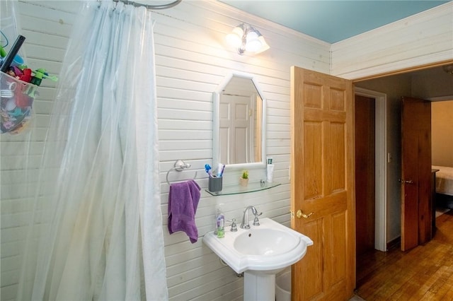 bathroom with wood finished floors, curtained shower, a sink, and wooden walls