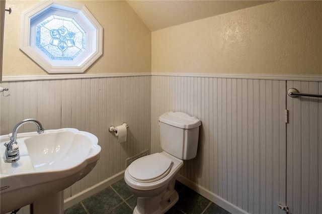 half bathroom featuring wainscoting, a sink, toilet, and tile patterned floors