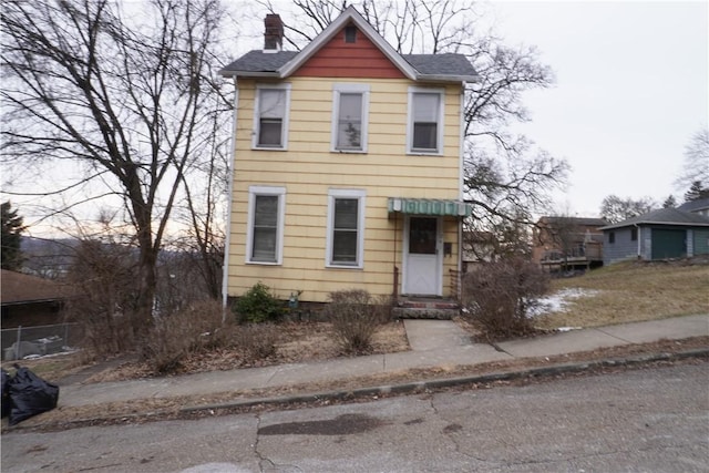 view of front of house featuring roof with shingles and a chimney