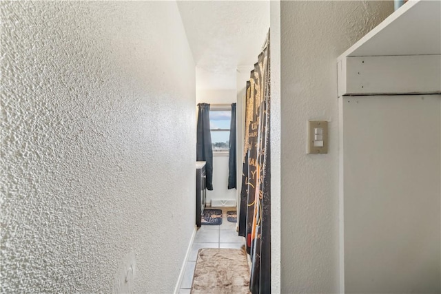 hallway with light tile patterned floors and a textured wall