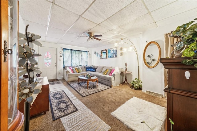 carpeted living area with a ceiling fan and a drop ceiling