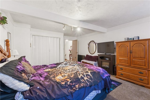 bedroom featuring a textured ceiling, carpet floors, a closet, and beamed ceiling