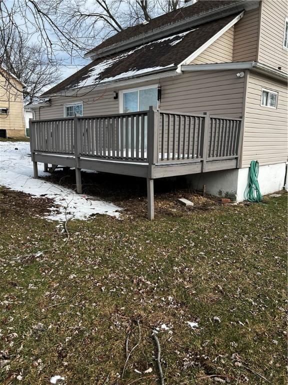 snow covered back of property featuring a yard and a wooden deck