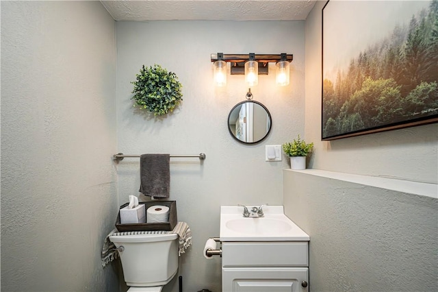 bathroom with toilet, a textured ceiling, and vanity