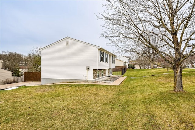 view of property exterior with a patio, a lawn, and fence