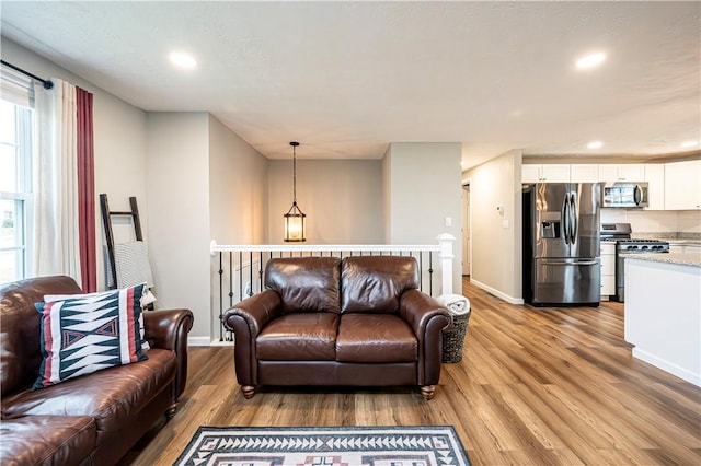 living area with light wood-style floors, recessed lighting, and baseboards