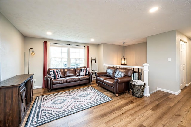 living area featuring baseboards, wood finished floors, and recessed lighting