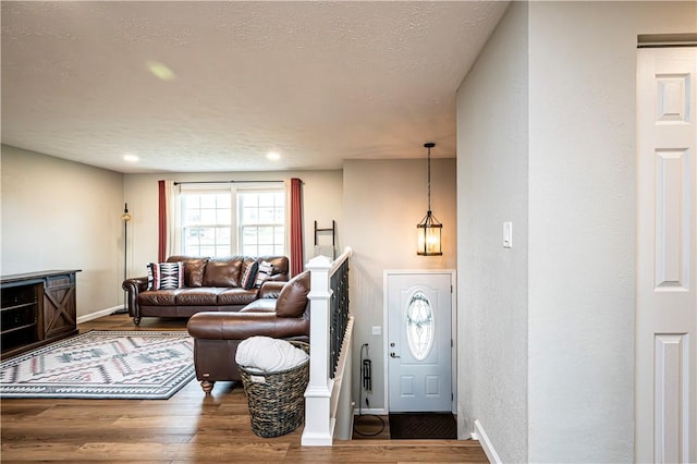 living area featuring dark wood-style floors, recessed lighting, a textured wall, a textured ceiling, and baseboards