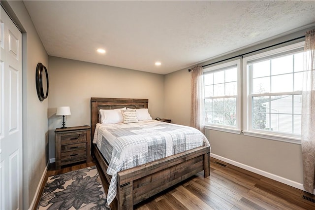 bedroom with recessed lighting, wood finished floors, visible vents, and baseboards