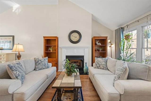 living room featuring a fireplace with flush hearth, high vaulted ceiling, and wood finished floors