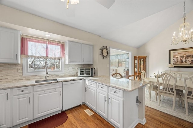 kitchen featuring white cabinetry, white dishwasher, a peninsula, and a sink