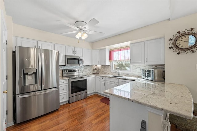 kitchen with a peninsula, white cabinetry, appliances with stainless steel finishes, and a kitchen breakfast bar