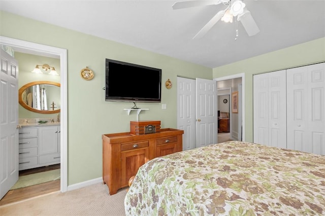 bedroom featuring light colored carpet, two closets, baseboards, and ensuite bathroom