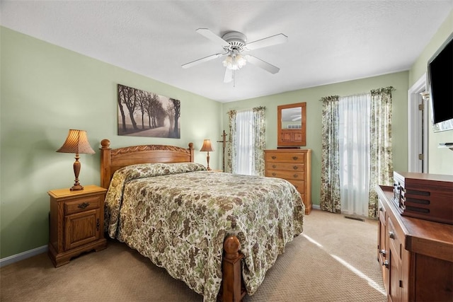 bedroom with ceiling fan, baseboards, a textured ceiling, and light colored carpet