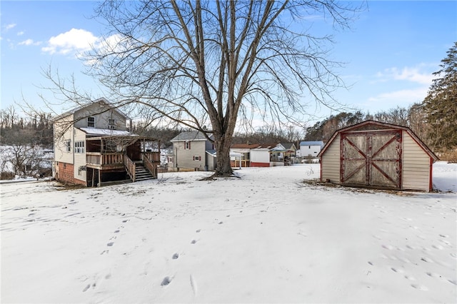 yard covered in snow featuring a storage shed, a detached garage, stairs, and an outbuilding