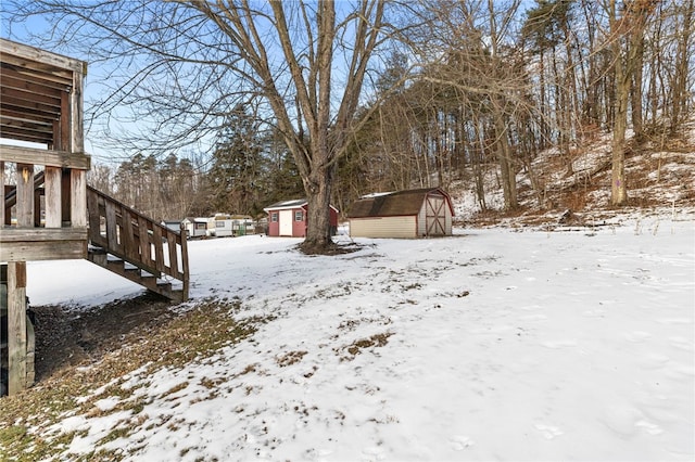 yard covered in snow featuring an outbuilding and a shed