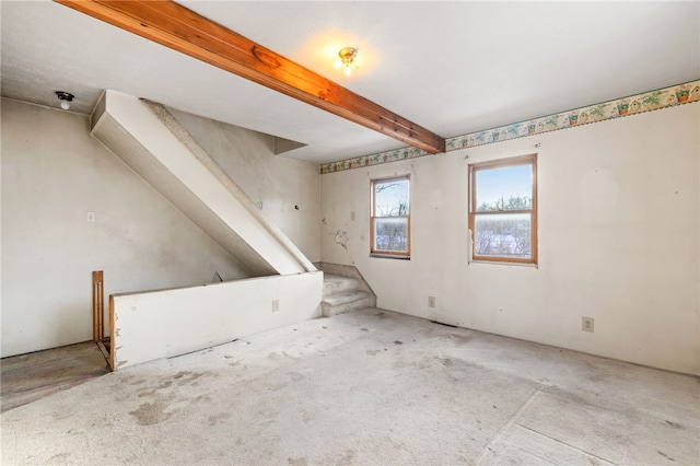 spare room with stairs and beam ceiling