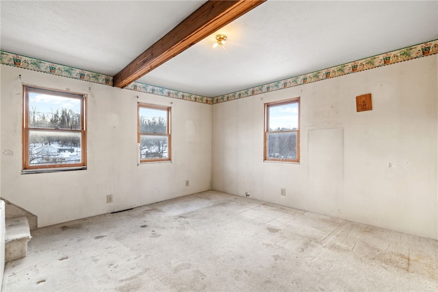 unfurnished room with beam ceiling, light colored carpet, and stairs