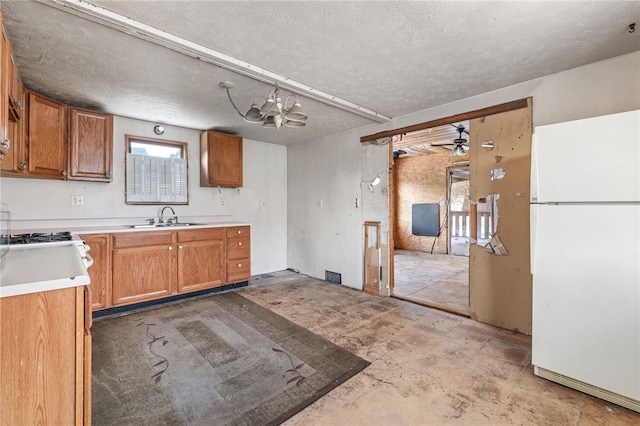 kitchen featuring brown cabinetry, light countertops, a sink, and freestanding refrigerator