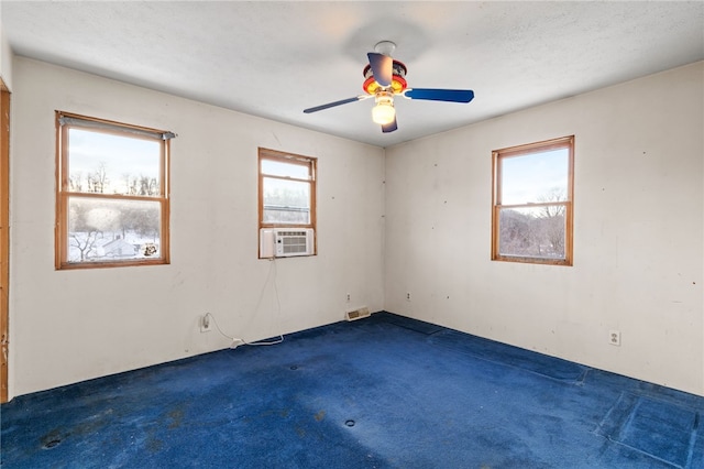 empty room featuring dark carpet, plenty of natural light, and cooling unit