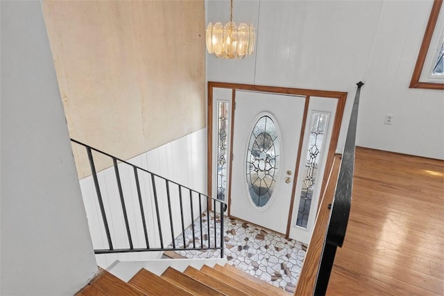 foyer entrance with light wood-style floors, a chandelier, stairway, and a towering ceiling