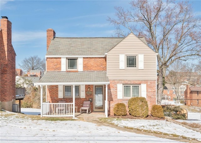 traditional-style house with brick siding, a chimney, and cooling unit