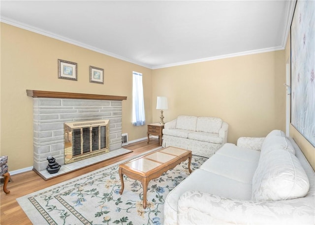 living room with baseboards, a stone fireplace, wood finished floors, and crown molding