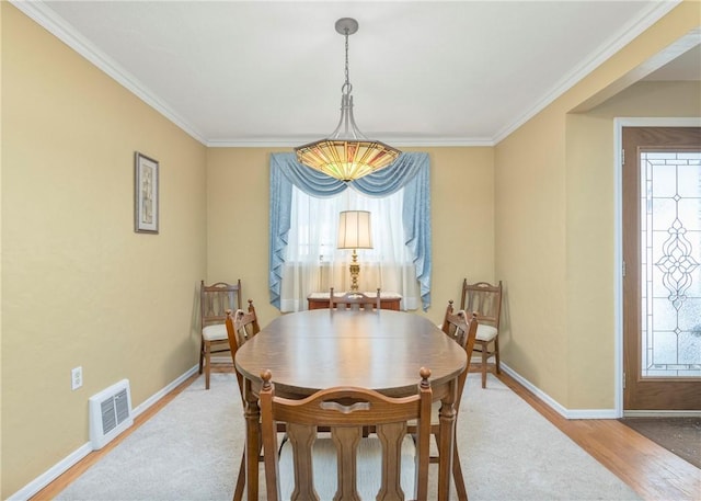 dining room with baseboards, crown molding, visible vents, and wood finished floors