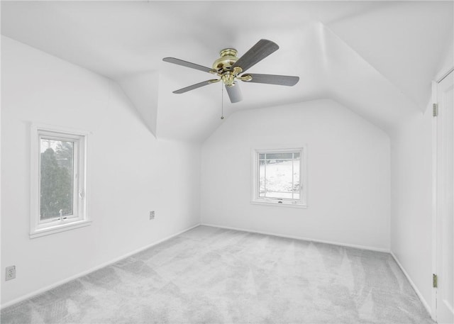 empty room featuring light colored carpet, vaulted ceiling, and ceiling fan