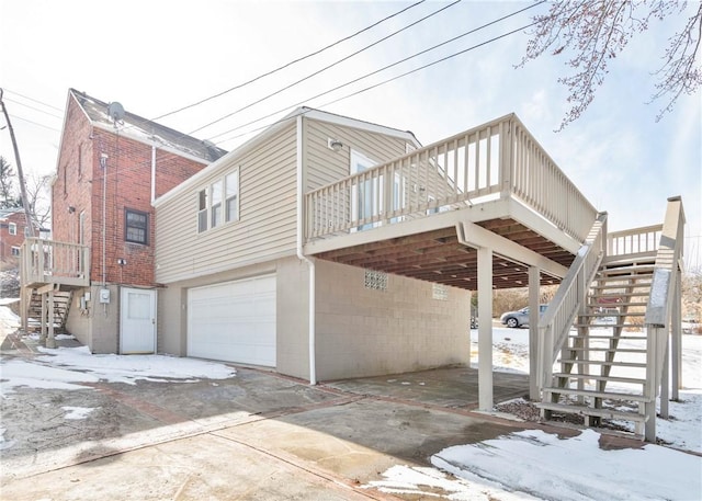 view of snowy exterior featuring stairs, a carport, a deck, and an attached garage