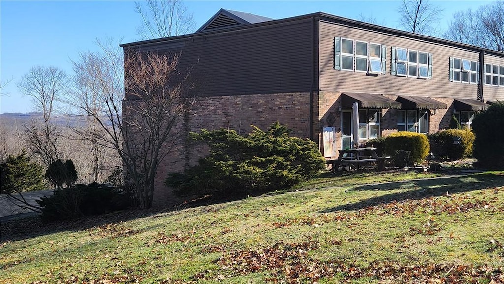 view of property exterior with brick siding and a yard