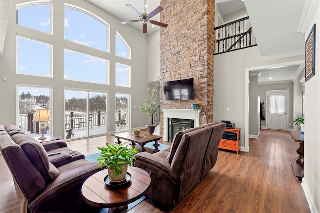 living room with crown molding, a fireplace, wood finished floors, and baseboards