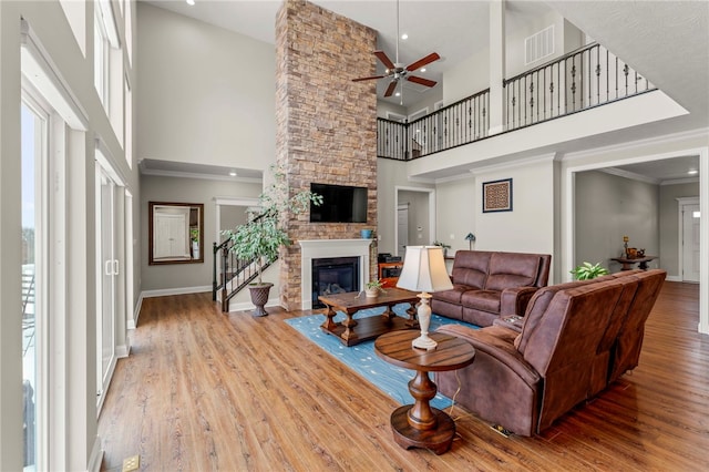 living area with visible vents, baseboards, light wood-style flooring, stairway, and a stone fireplace