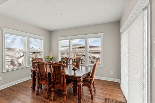 dining space featuring dark wood-style floors, a textured ceiling, and baseboards