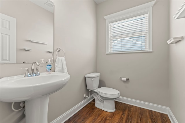 half bathroom featuring visible vents, wood finished floors, toilet, and baseboards