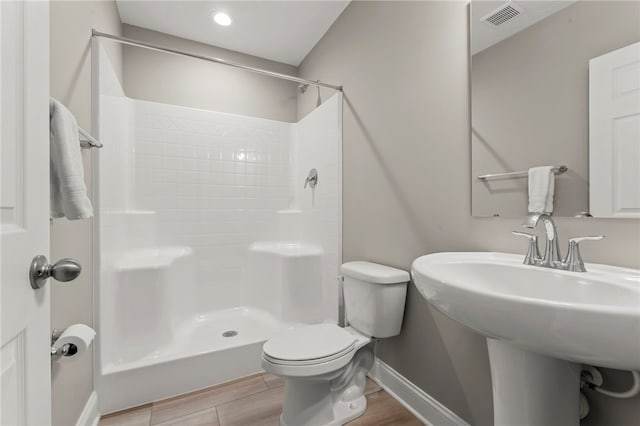 full bath with toilet, wood finished floors, visible vents, baseboards, and a shower stall