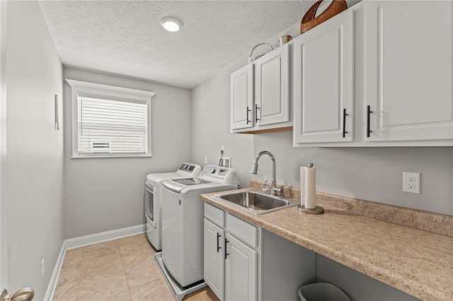 laundry area with a textured ceiling, separate washer and dryer, a sink, baseboards, and cabinet space