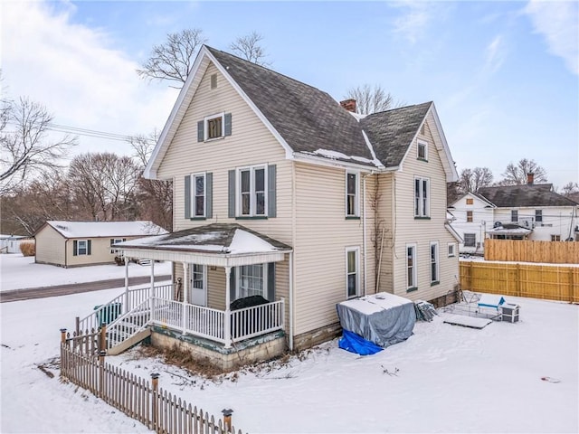 view of front of home featuring a porch, a chimney, and fence