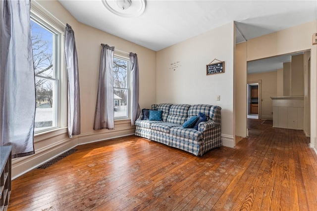 living area with baseboards, visible vents, and wood finished floors